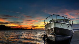The front of a boat in the lake, something that you might holiday on for a weekend or longer.