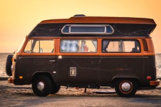 An old style campervan with the sun setting in the background